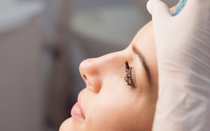 Hands of doctor examining womans face for cosmetic treatment at clinic